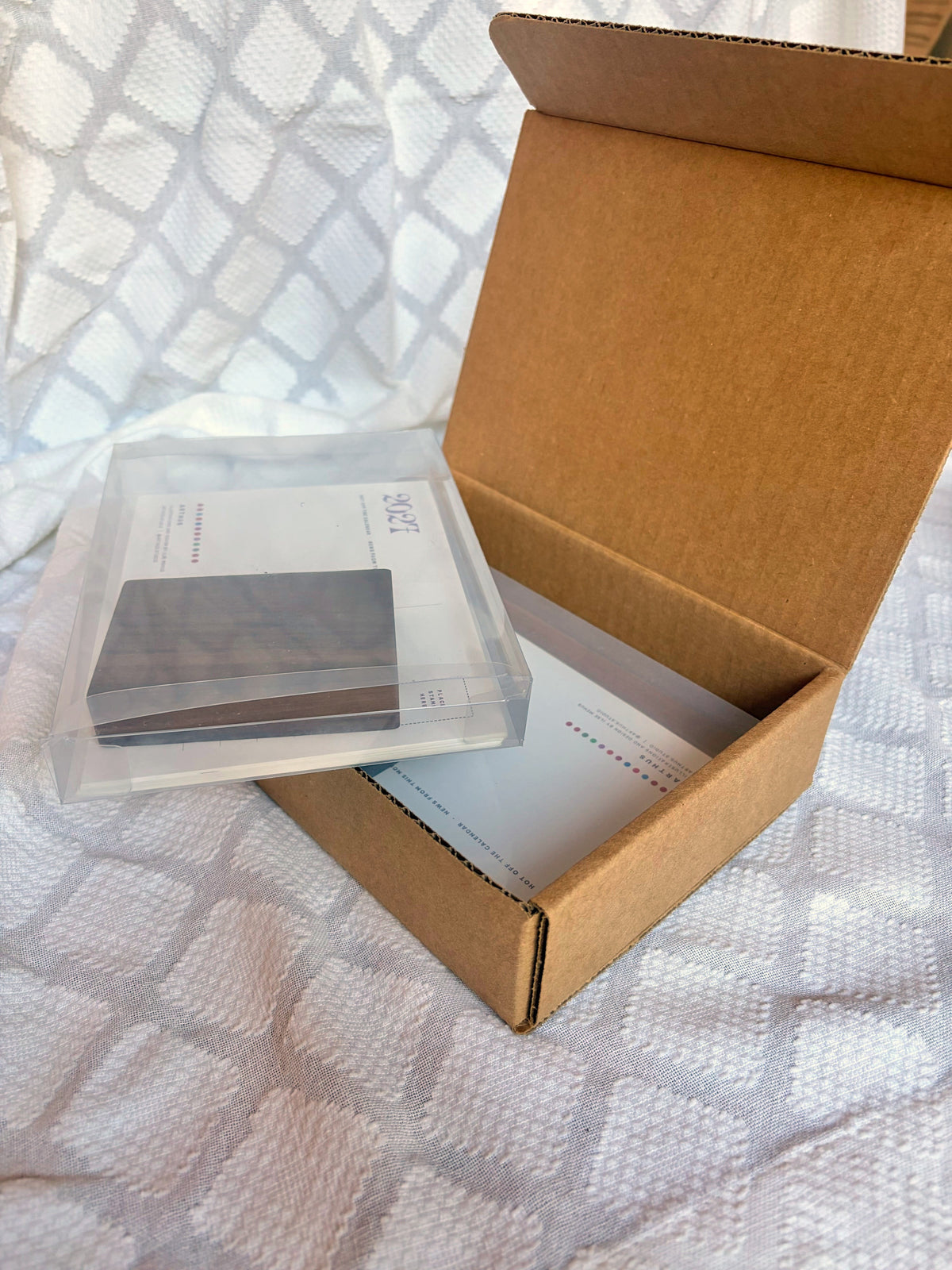 calendar in clear acrylic box with walnut stand, packed in a kraft shipping mailer