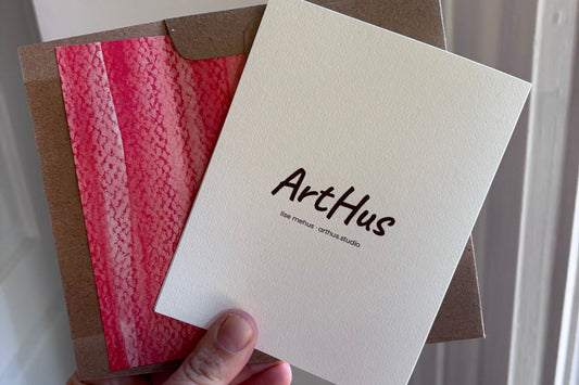 back of an arthus holiday card with a red-lined kraft envelope