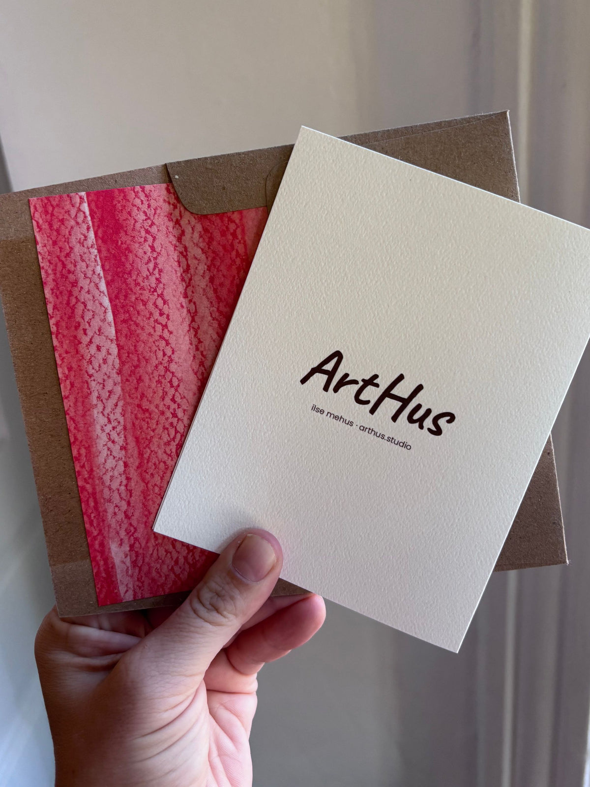back of an arthus holiday card with a red-lined kraft envelope